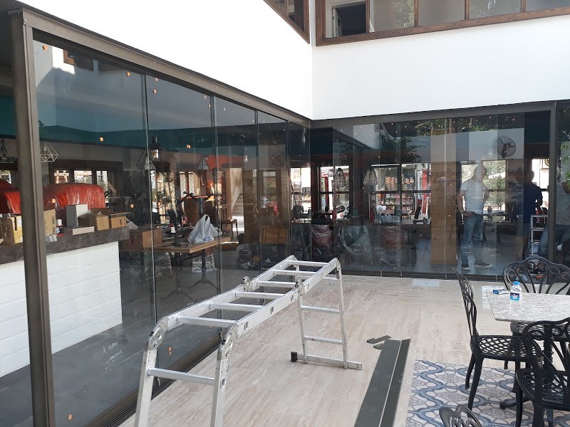 Sürme cam sistemiyle kapatılan kafe oturma alanı